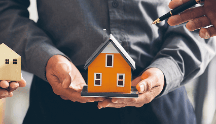 Home inspection with a model house held by a professional in a suit.