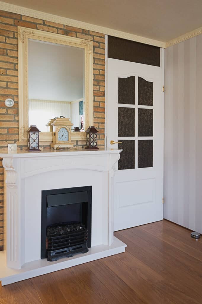 Fireplace with white mantel, mirror, and decorative accents in a cozy living room.