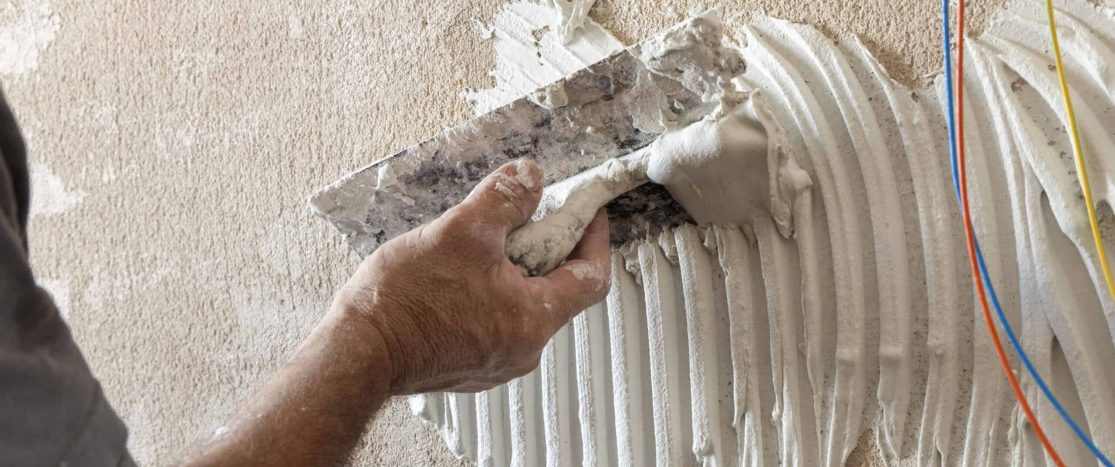 Skilled worker applying plaster to wall with trowel for smooth finish.