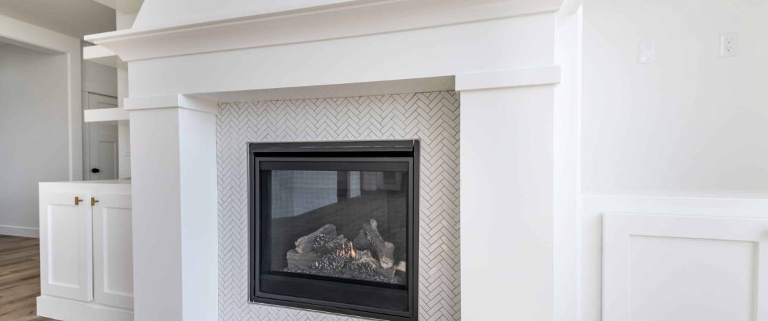 Fireplace with white mantel and decorative tile surround, showcasing professional plaster and finish.
